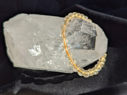 Premium 6mm Golden Rutilated Quartz beaded stretch bracelet worn on the wrist to demonstrate its 17cm circumference scale and continuous mineral profile under balanced lighting.