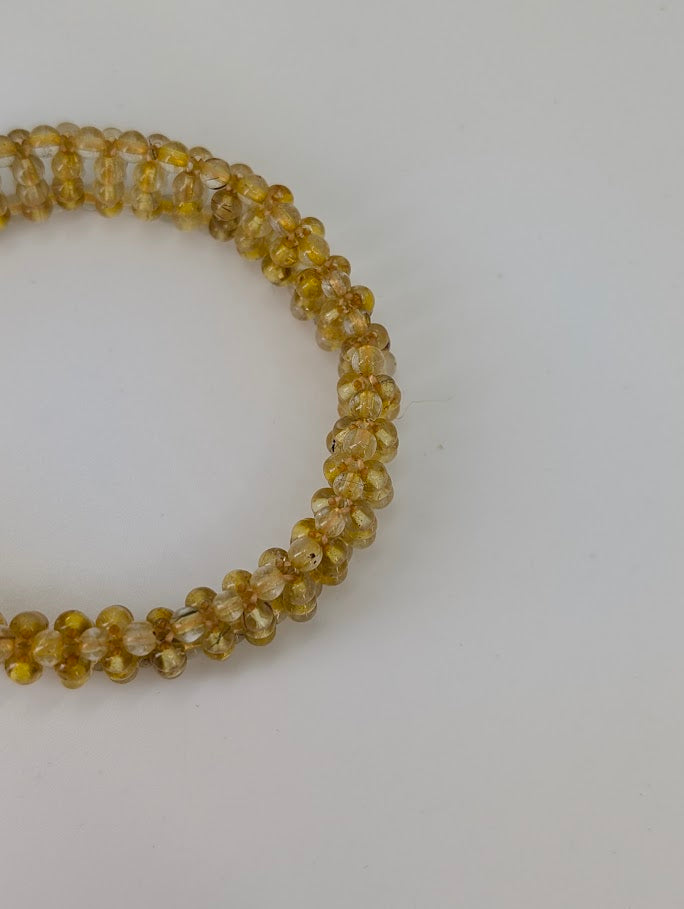 Close-up of golden rutile inclusions inside translucent quartz beads