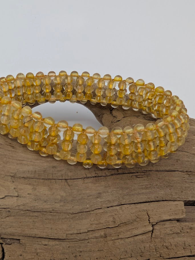 Close-up of golden rutile inclusions inside translucent quartz beads