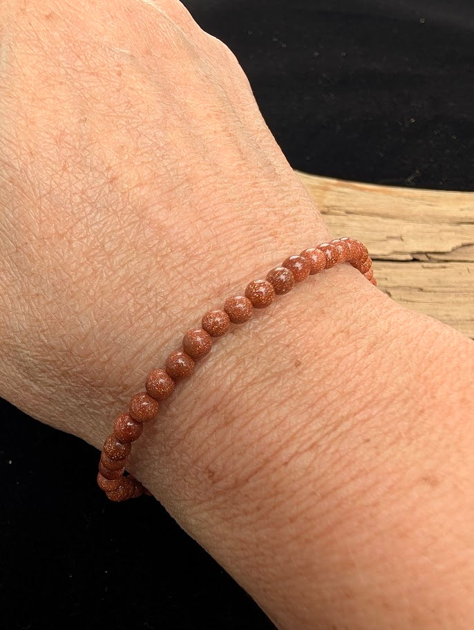 4mm polished Golden Sandstone beaded stretch bracelet worn on a wrist for delicate size scale.