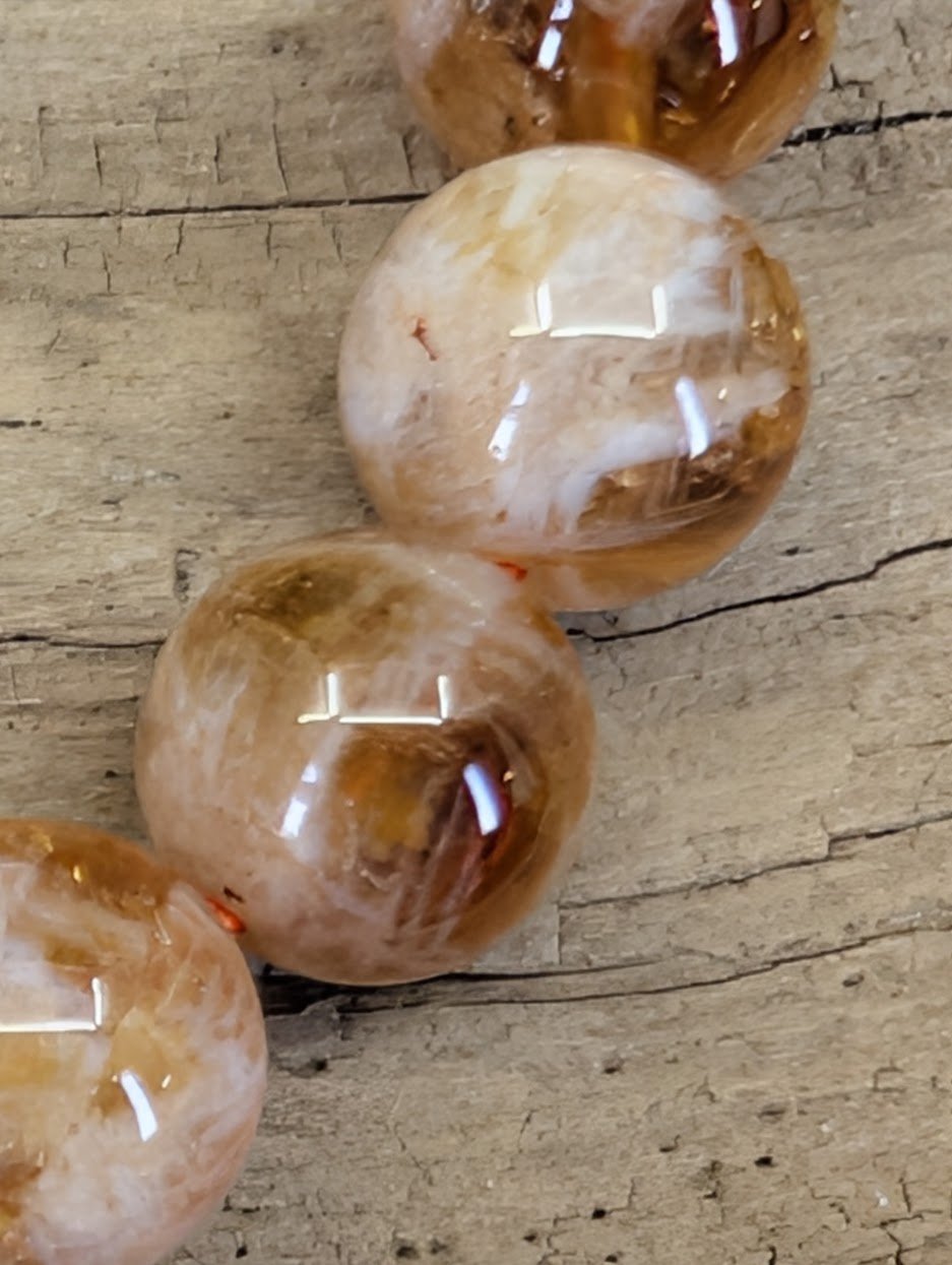 Extreme close-up of natural inclusion quartz beads highlighting the fiery orange sericite phantoms and high-clarity crystal.
