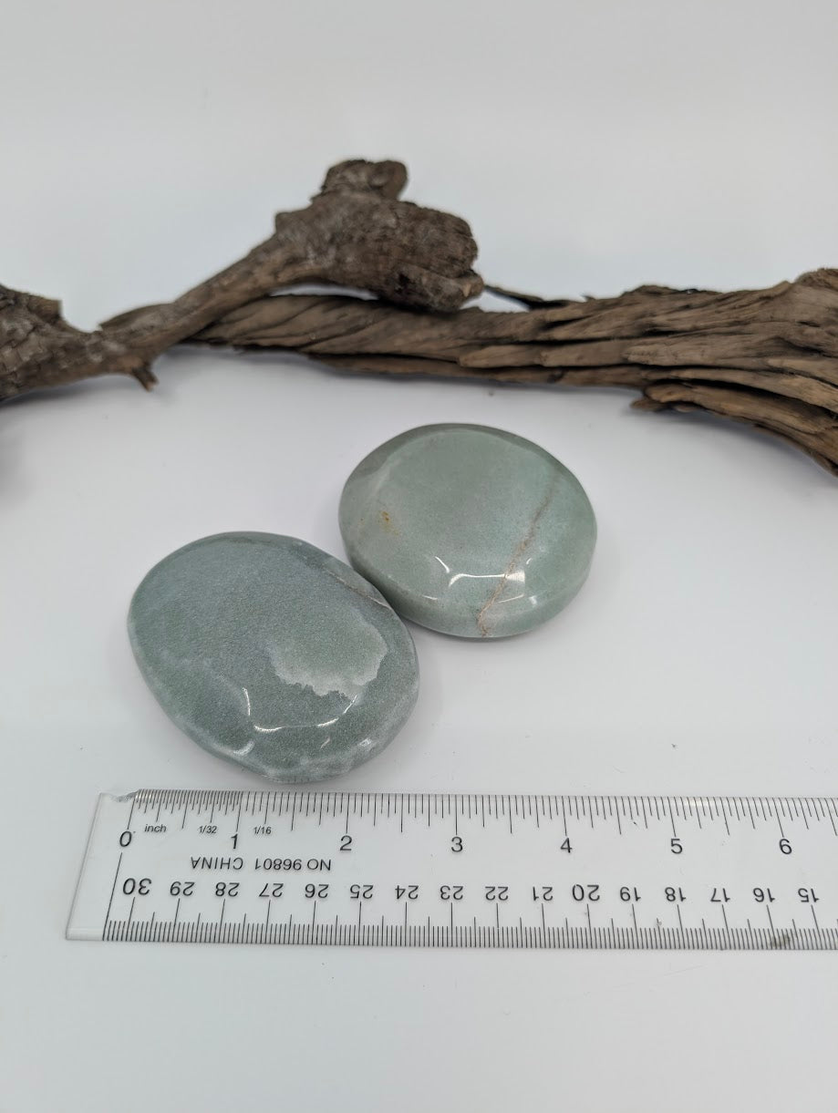 Large green aventurine palm stone beside ruler showing approximate size