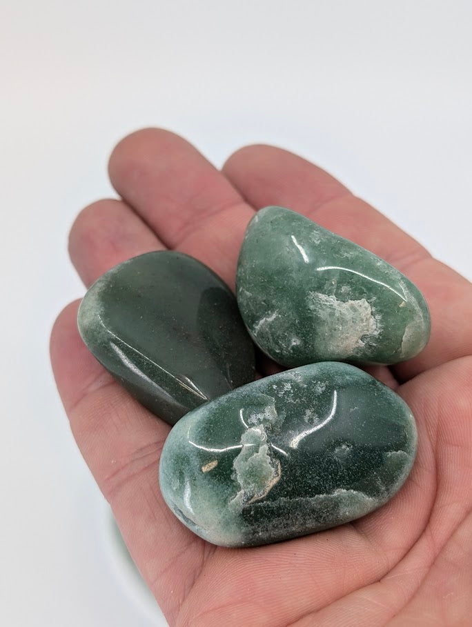 Green Aventurine tumbled stones shown in hand for scale