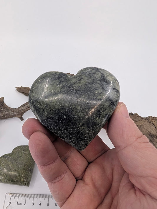 Hand holding a large 160g Dark Green Jade heart showing white veins.