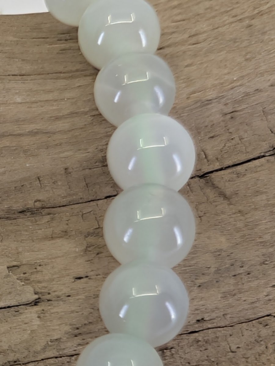Macro view of 6mm Garnierite beads showing high-gloss polish and authentic moonstone light play.