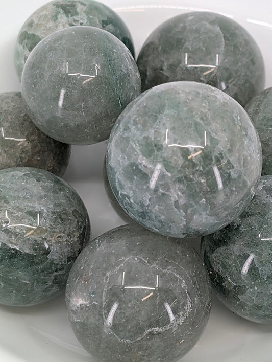 Close-up of polished Green Strawberry Quartz spheres with shimmering inclusions