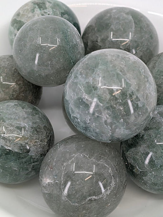 Close-up of polished Green Strawberry Quartz spheres with shimmering inclusions