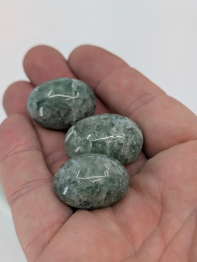 Green Strawberry Quartz tumbled stones shown in hand for scale