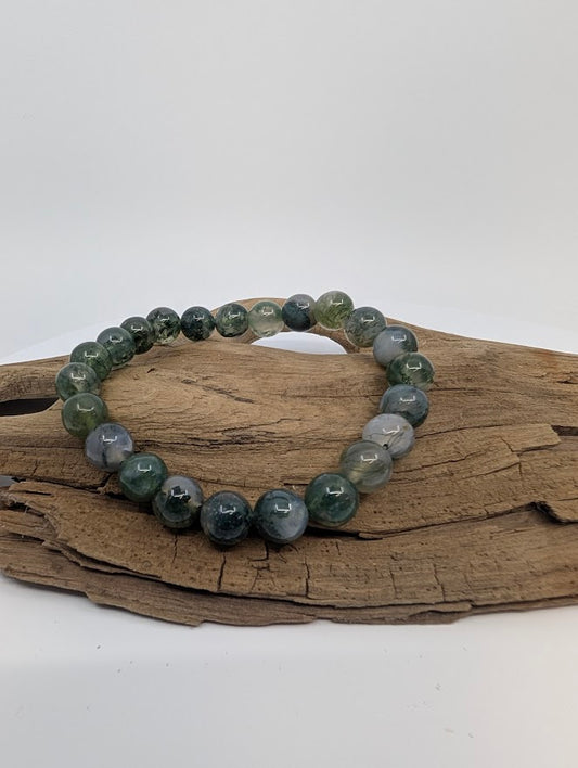 High-quality 8 mm Moss Agate bracelet on driftwood, full bracelet view.