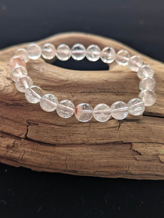 Intuitively selected 9mm AAA Grade Himalayan Garden Quartz beaded stretch bracelet on a driftwood display, showing ice-clear quartz with natural scenic mineral inclusions.