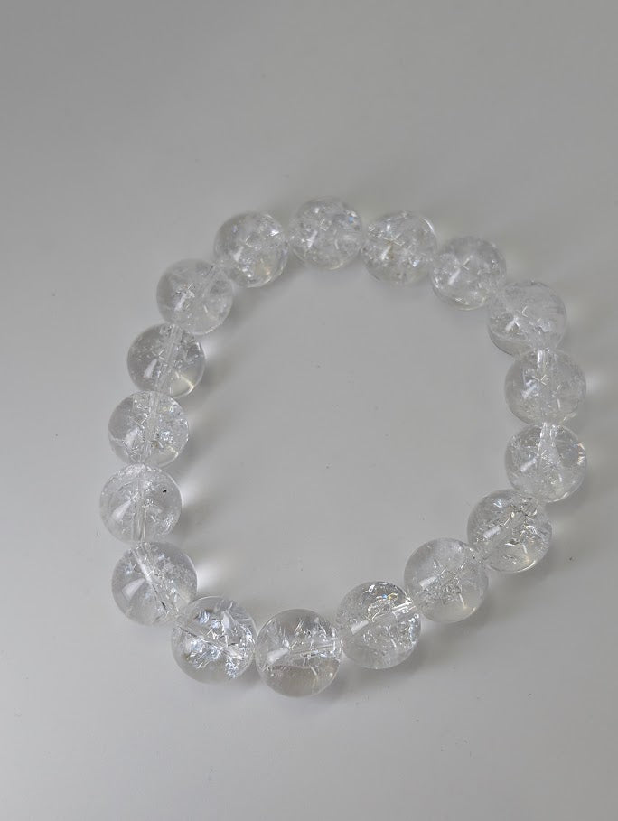 Top-down view of 12mm Himalayan quartz bracelet on neutral background