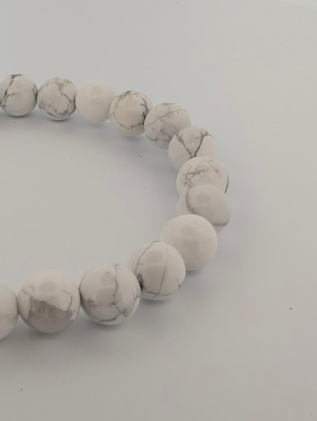 Angled close-up of 8mm Howlite round beads with polished finish and natural veining