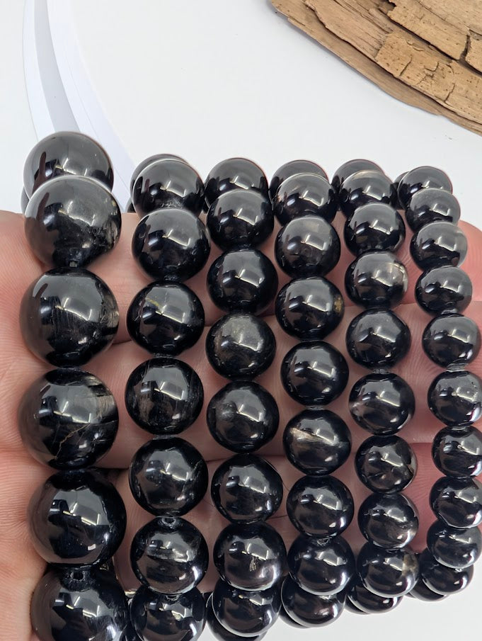 Handheld view of Hypersthene bracelets at an angle emphasizing metallic flash and polish