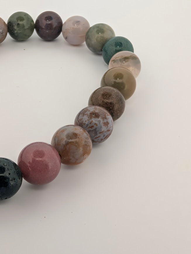 Angled close-up of 8mm Indian Agate beads with translucent windows and mottled greens and reds