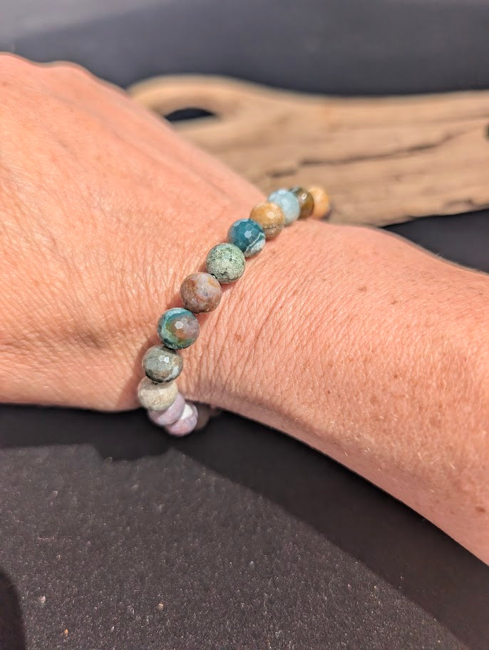 Natural sunlight on a faceted 8mm multi-coloured Indian Agate stretch bracelet worn on a wrist.