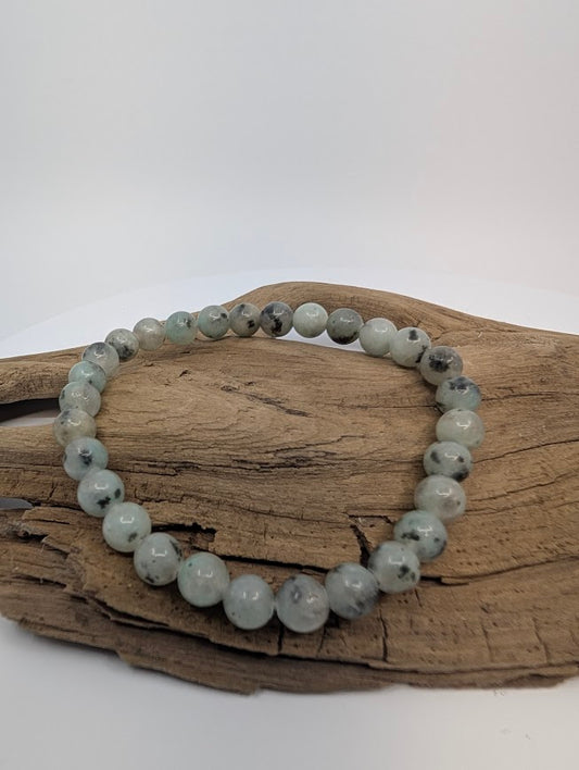 Kiwi Jasper 8mm round bead stretch bracelet on driftwood showing mint-green color with black speckles