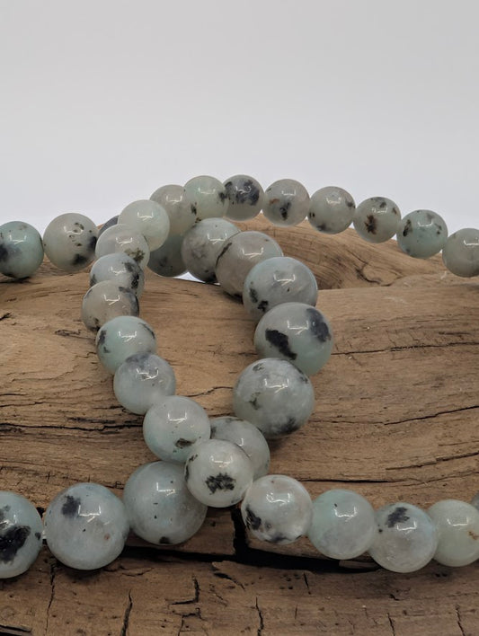 Close-up of Kiwi Jasper beads showing mint-green color with charcoal speckles.