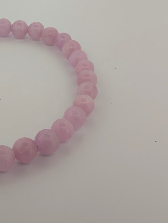 Angled close-up of Kunzite beads highlighting translucent glow and natural variation