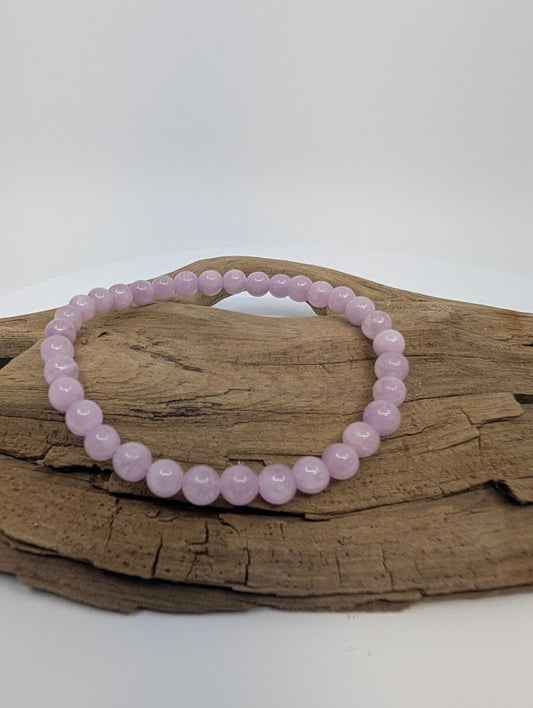 Kunzite 6mm round bead stretch bracelet on driftwood showing soft lilac-pink tones
