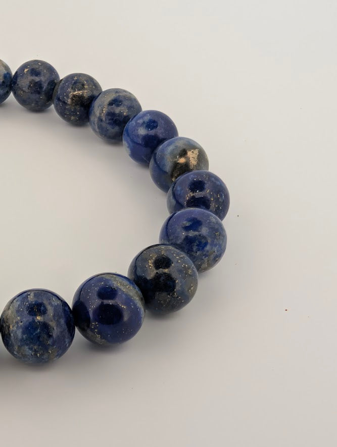 Macro detail of polished 8mm Lapis Lazuli beads showing blue matrix and gold flecks.