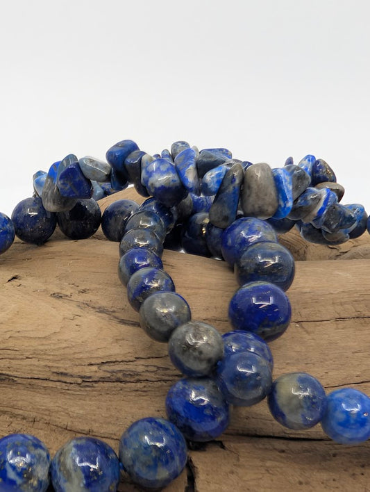 Closeup of Lapis Lazuli chips and round beads showing royal blue color with gold pyrite flecks.