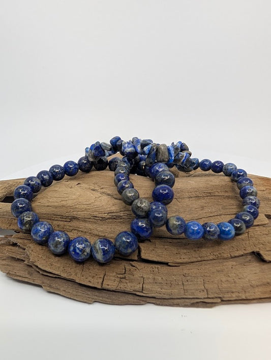 Three Lapis Lazuli stretch bracelets—chip, 6mm, and 8mm—styled together on driftwood