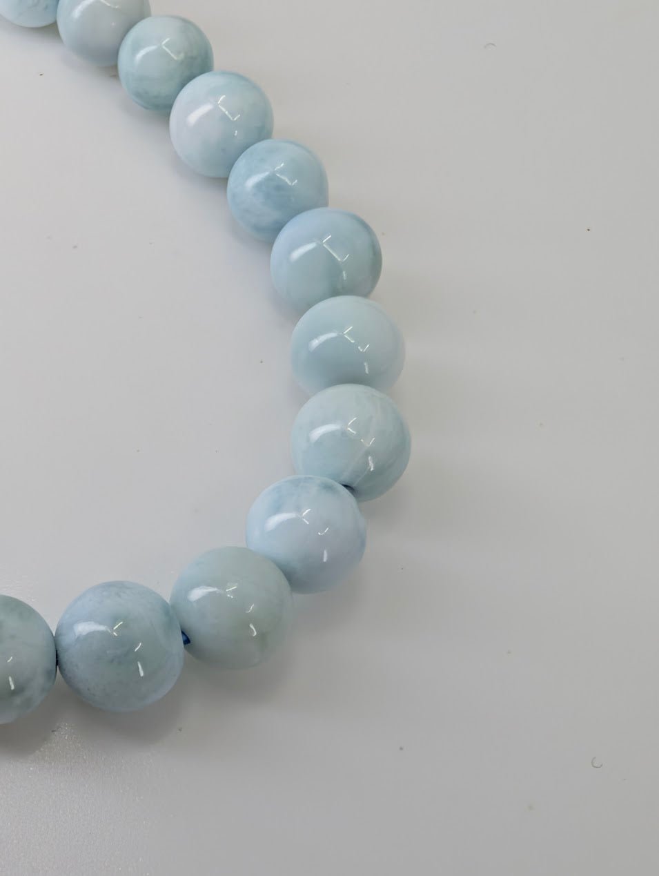Detail shot of pale blue 6mm Larimar beads showing polish and texture