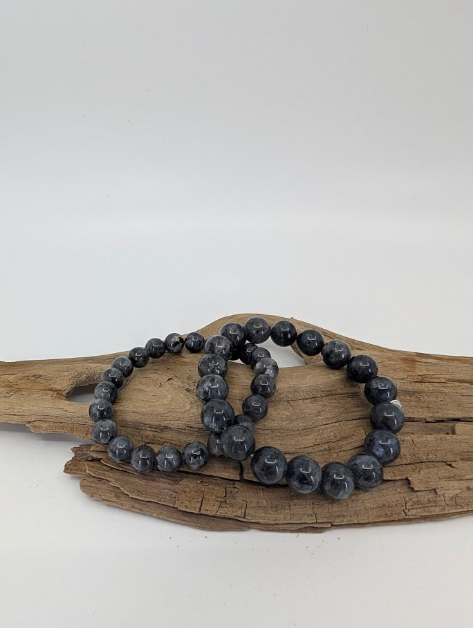 Larvikite bracelet with 8mm and 10mm round beads on driftwood, front angle