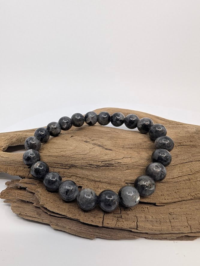 Larvikite bracelet with 8mm round beads on driftwood, front angle