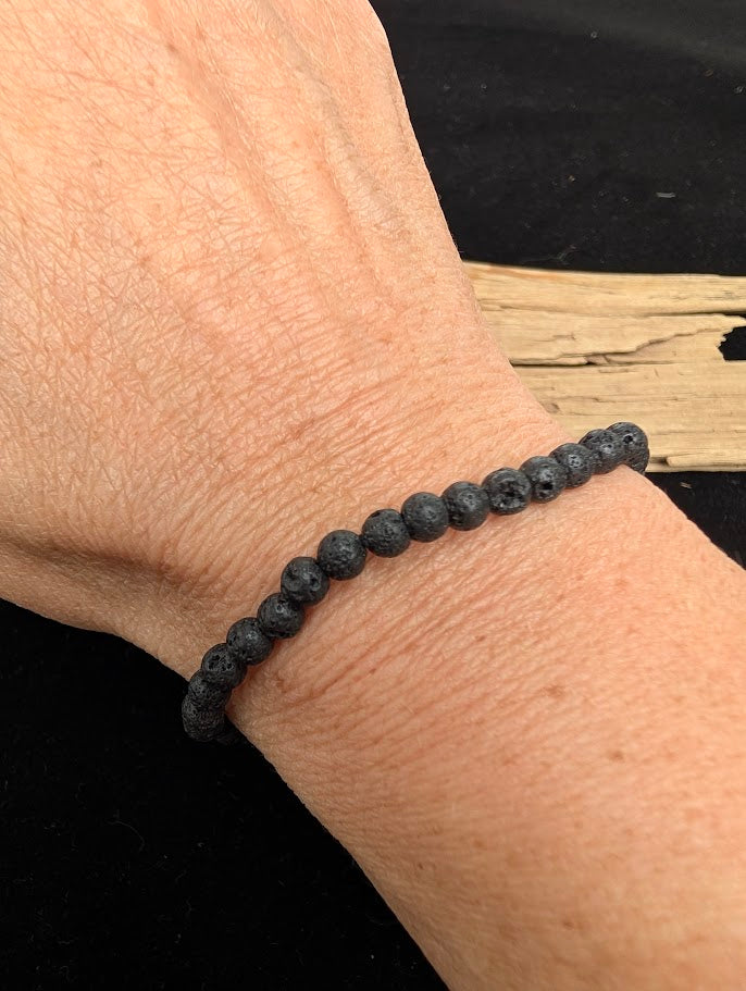 4mm Lava Stone beaded stretch bracelet worn on a wrist for delicate size scale.