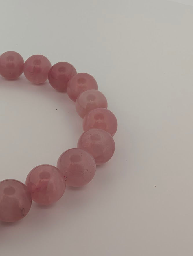 Angled view of 8mm lavender rose quartz bracelet with glossy polish