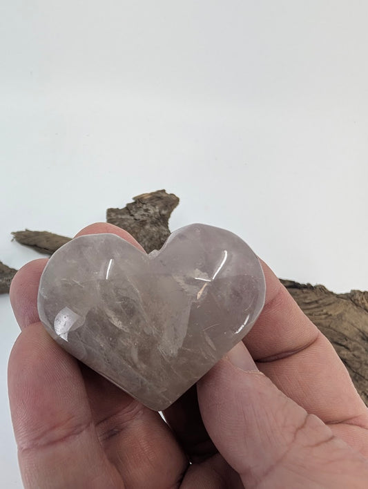 Hand holding a 70g Lavender Rose Quartz heart showing jelly translucency.