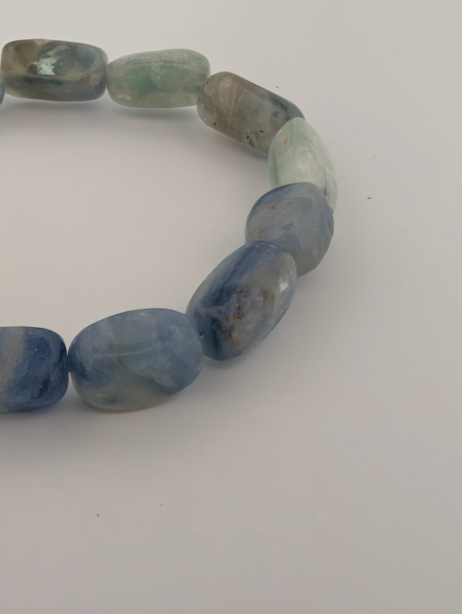 Angled macro of Blue Kyanite beads with soft aqua zoning and polished finish