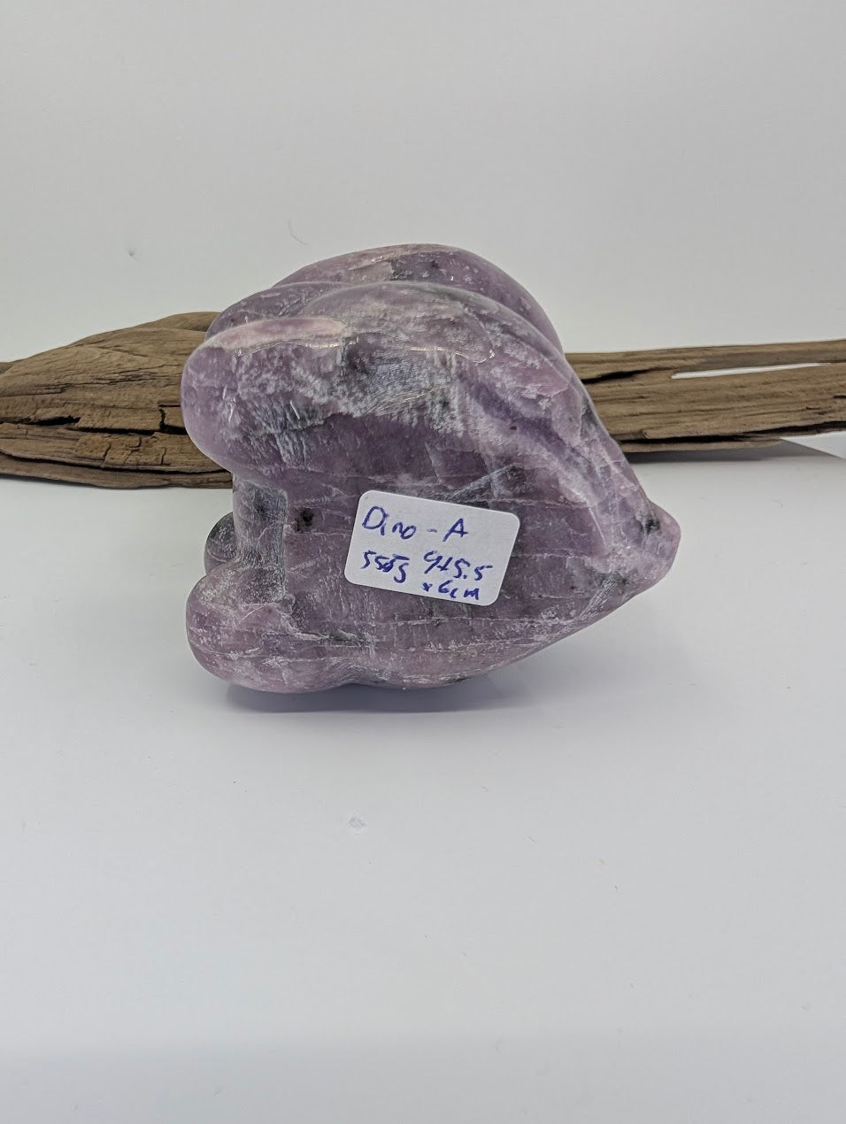 Underside of Lepidolite dinosaur specimen A with 558g weight label and raw mineral texture.