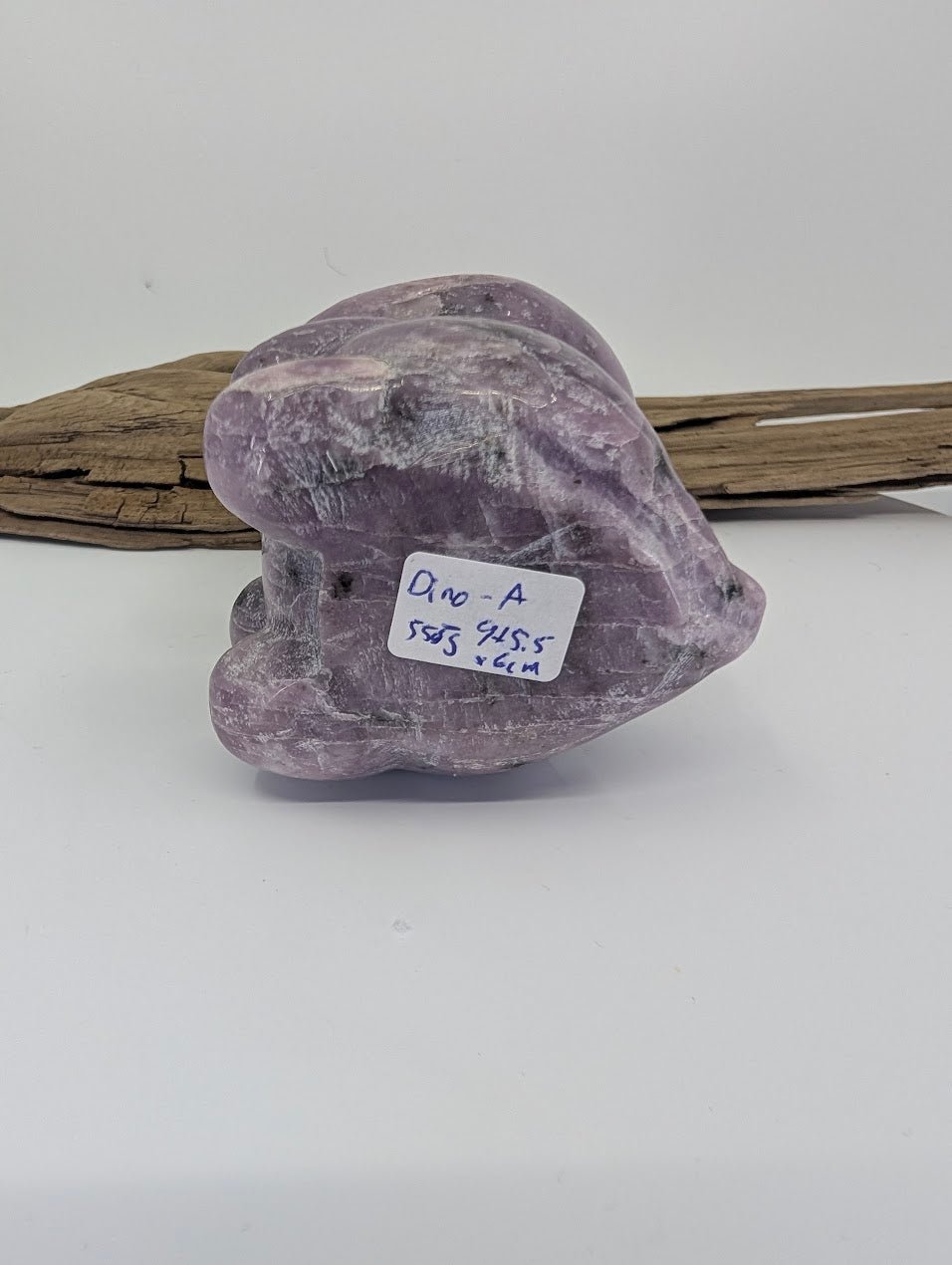 Underside of Lepidolite dinosaur specimen A with 558g weight label and raw mineral texture.