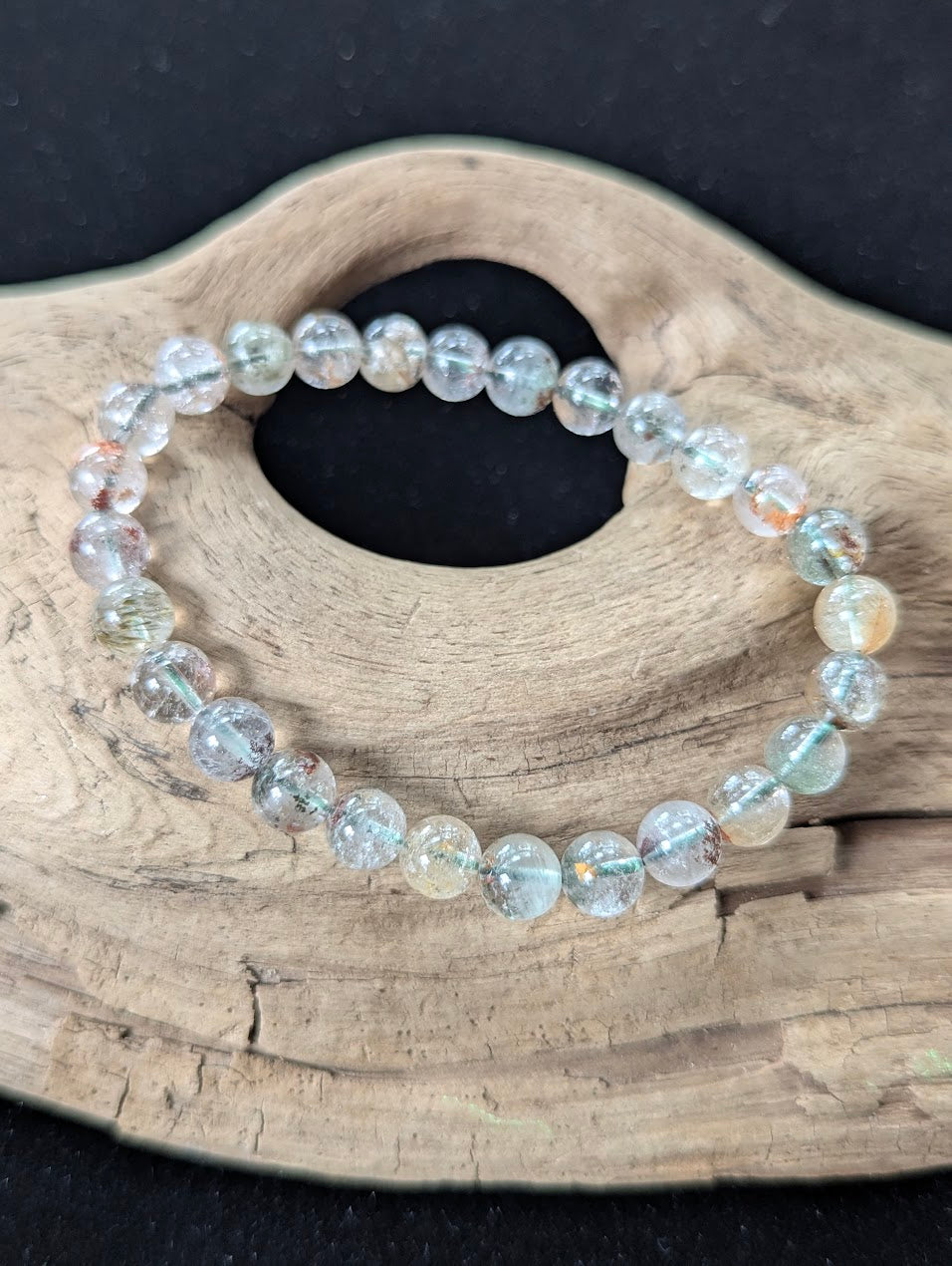 7mm Light Garden Quartz (Lodolite) Bracelet, showing delicate multi-coloured inclusions resting on driftwood.