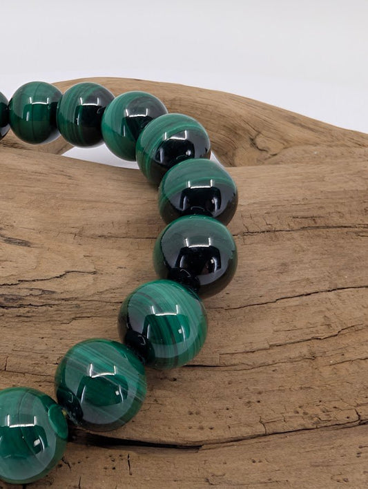 Close-up of 10mm malachite beads on wood highlighting polished surface and natural banded patterns