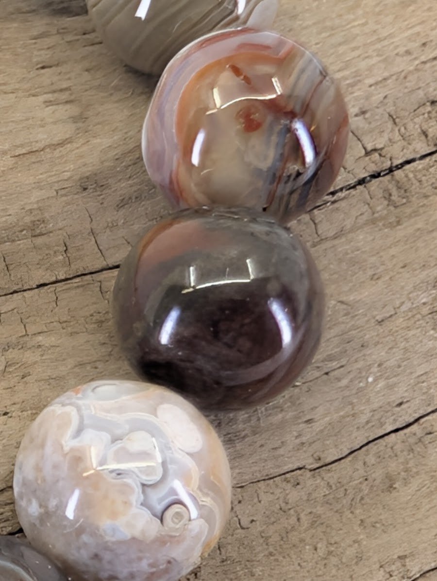 Macro view of Mexican Lace Agate beads showing high-gloss polish and authentic fortification agate structures