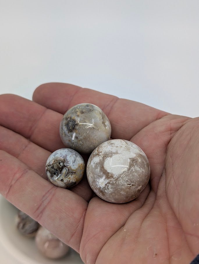 Three Mexican Lace Agate mini spheres in hand for size reference