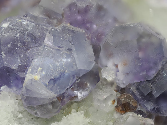 Macro photography of violet Fluorite crystal faces showing natural etching and growth patterns.