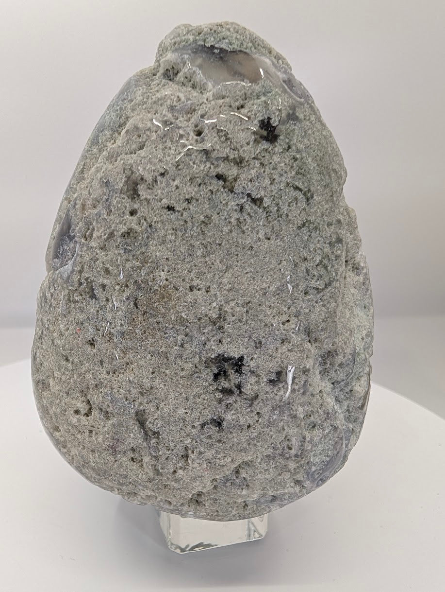 Hand-held moss agate egg showing scale, weight, and natural surface features