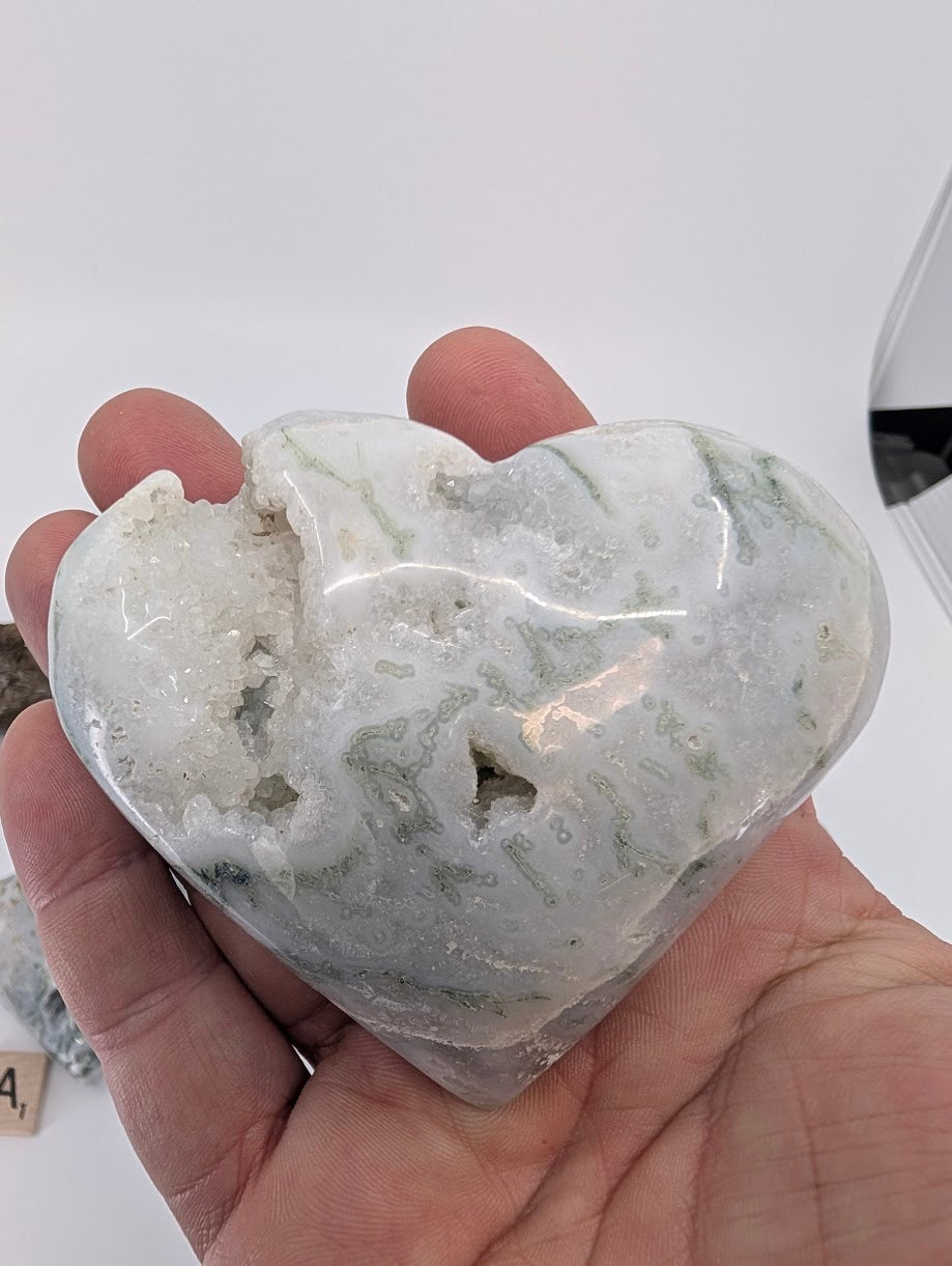 Hand holding Specimen C, a large 280g Moss Agate heart with central crystal cave.