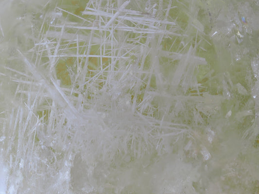 Extreme macro view of dense white acicular inclusions forming a lattice structure within the citrine quartz.