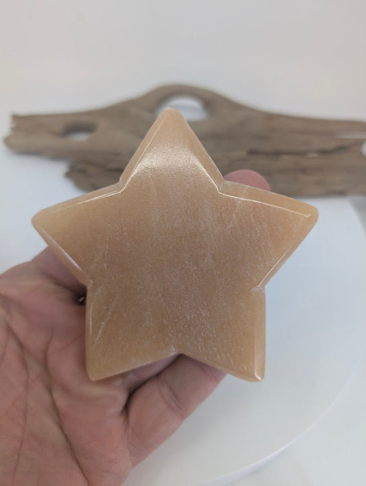 Close-up of a 91mm Orange Calcite star showing the high-luster polished finish, internal white veiling, and natural translucency.