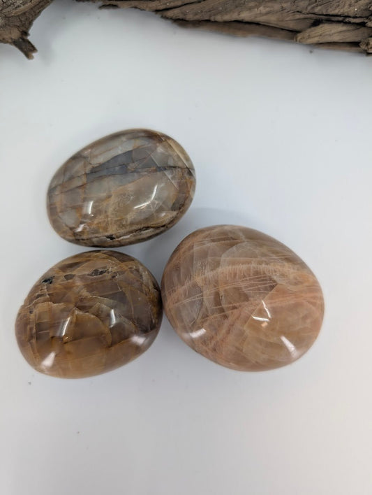 Group of Peach Moonstone palm stones showing natural feldspar structure and color variation