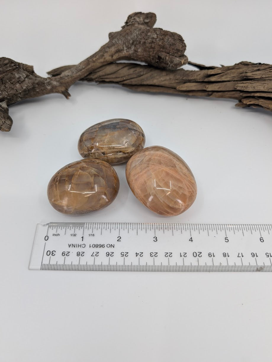 Peach Moonstone palm stones with ruler showing approximate size and thickness