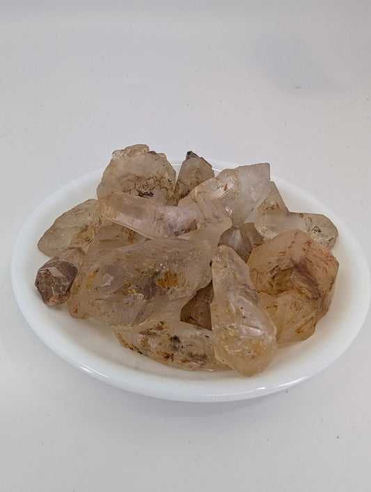 Petroleum Quartz point with hydrocarbon inclusions glowing under light