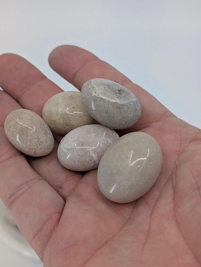 Pink Amethyst tumbled stones shown in hand for scale
