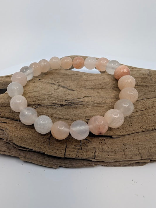 Pink Aventurine 8mm beaded stretch bracelet displayed on driftwood, polished blush-peach beads