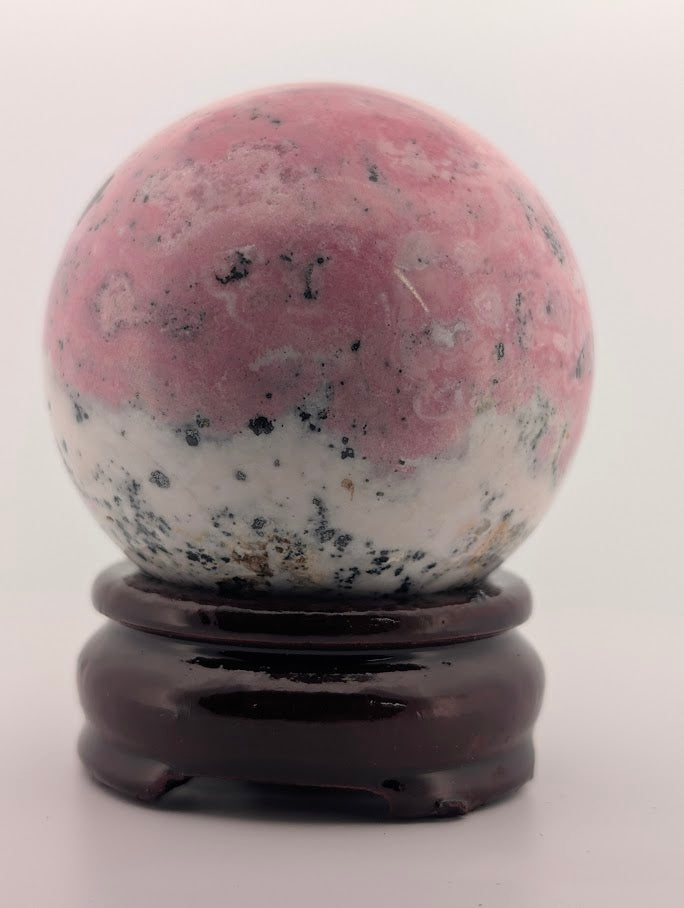 Polished rhodonite sphere side angle with manganese inclusions